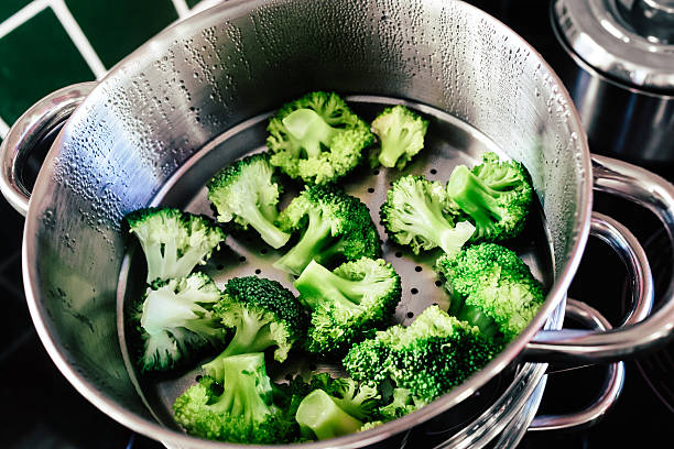 Broccoli cooked in steamer Broccoli florets being cooked in a steamer. Steamed Broccoli stock pictures, royalty-free photos & images