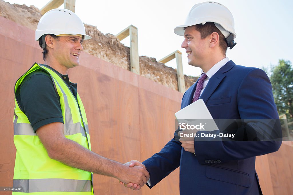 Businessman Shaking Hands With Builder On Construction Site Construction Site Stock Photo