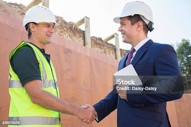 Businessman Shaking Hands With Builder On Construction Site Stock Photo - Download Image Now