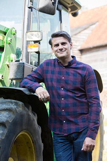 istock Portrait Of Farmer Standing Next To Tractor 610570888
