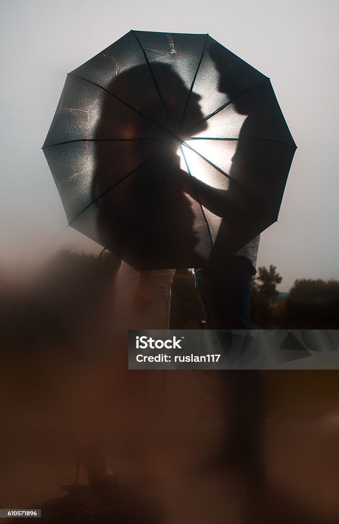 Love in the rain Silhouette of kissing couple under umbrella Love in the rain / Silhouette of kissing couple under umbrella Adult Stock Photo