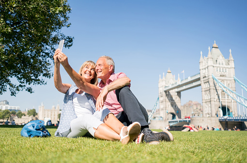 Happy couple of tourists in London taking a selfie with Tower Bridge at the background