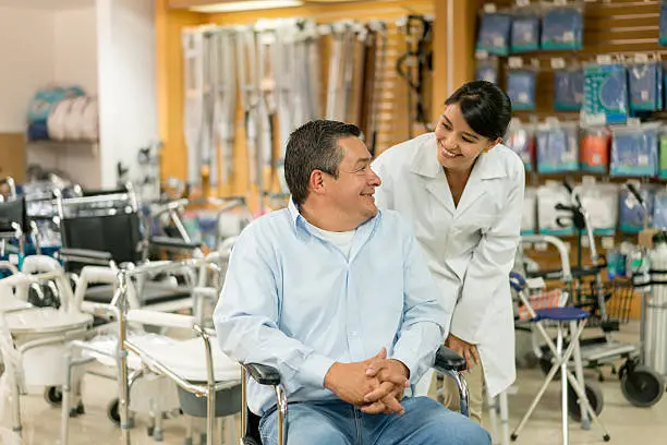 Orthopedist helping disabled man at a health store - medicine concepts