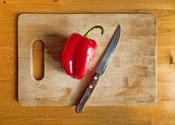 istock Red bell pepper and knife on wooden cutting board 610574030