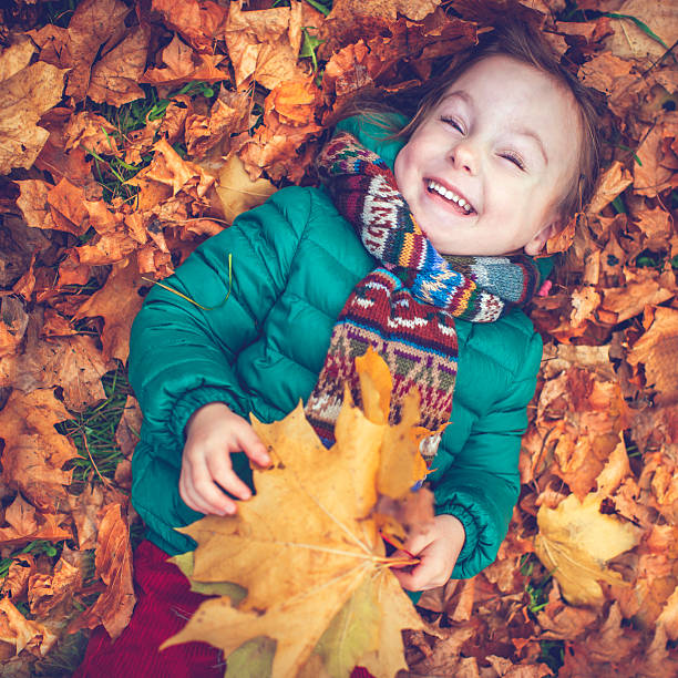 Happy child laying in leaves in autumn