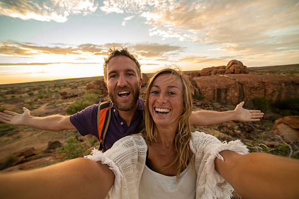 joven pareja toma retrato selfie con espectacular paisaje al amanecer - devils marbles fotografías e imágenes de stock