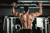 Athlete muscular fitness male model pulling up on horizontal bar