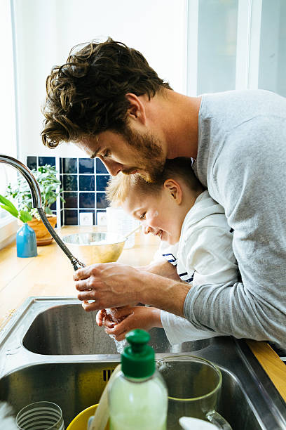 istock Father Washing Sons Hands In Kitchen Sink After Cooking Together 610581150