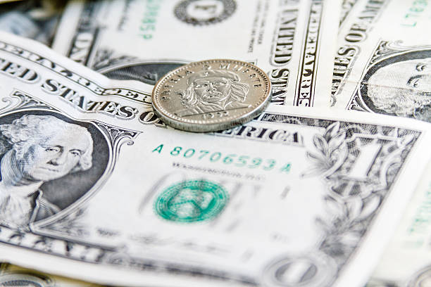 istock Coin three Cuban pesos over several dollar bills 610581628
