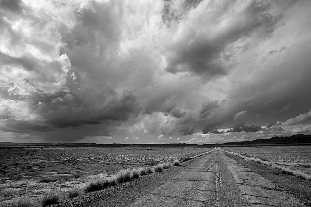 istock Old Desert Road Under Dramatic Cloudy Sky Black and White 610582276