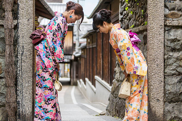 Traditionally dressed Japanese business women wearing kimonos bow when meeting each other in the Gion area of Kyoto, Japan