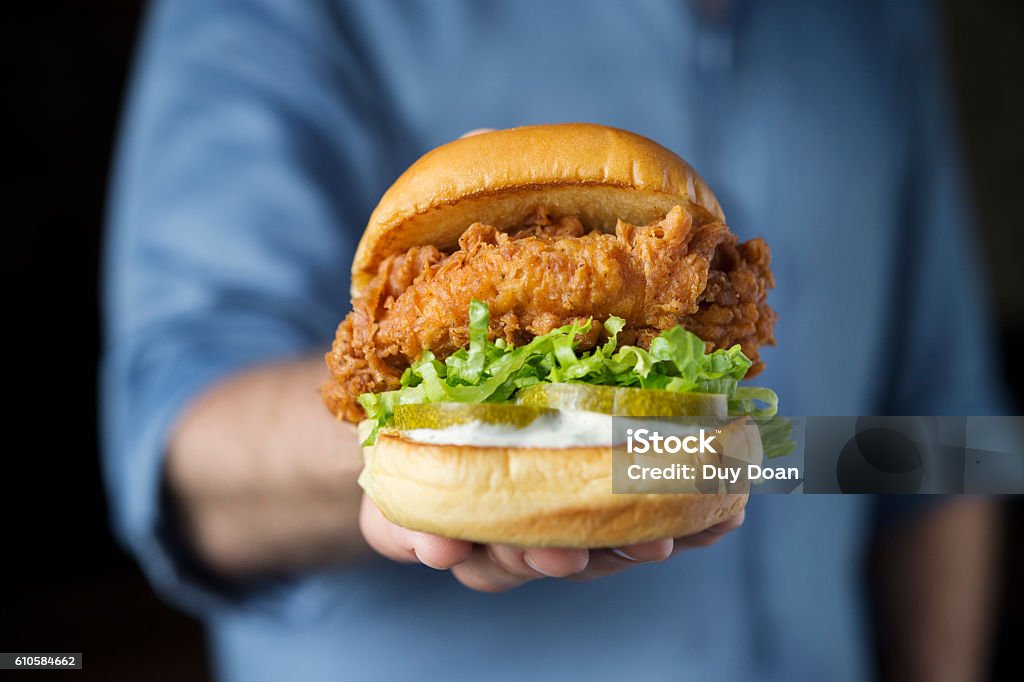 Shack fried chicken hamburger with lettuce and sliced cucumber o Shack fried chicken hamburger with lettuce and sliced cucumber on man's hand Backgrounds Stock Photo