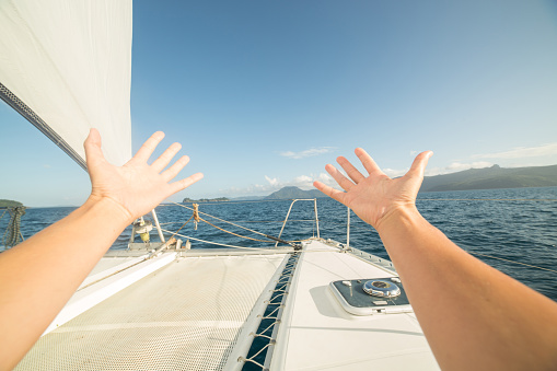 Pov of person on sailing boat stretches arms for freedom and positive emotions. 