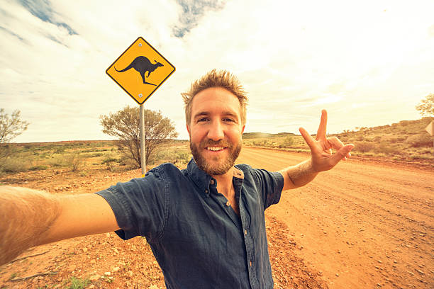 selfie d’un jeune homme en australie debout près du signe kangourou - emu australia northern territory outback photos et images de collection