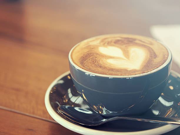 istock Cappuccino coffee in black cup on wooden table, Soft focus 610648856