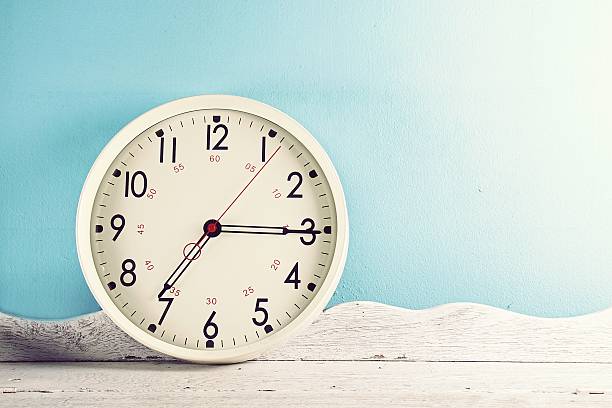 istock Vintage white wall clock on wooden table 610649944