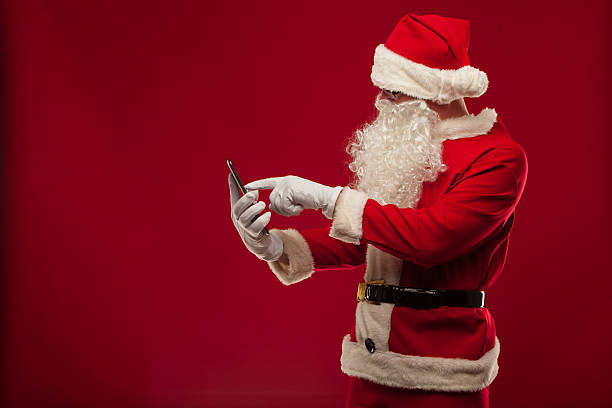 istock Modern Santa Claus using tablet pc over red background. Christma 610650384