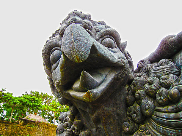 A fierce stone guardian statue with intricate carvings stands at the entrance of a Balinese temple, symbolizing protection and spiritual power.