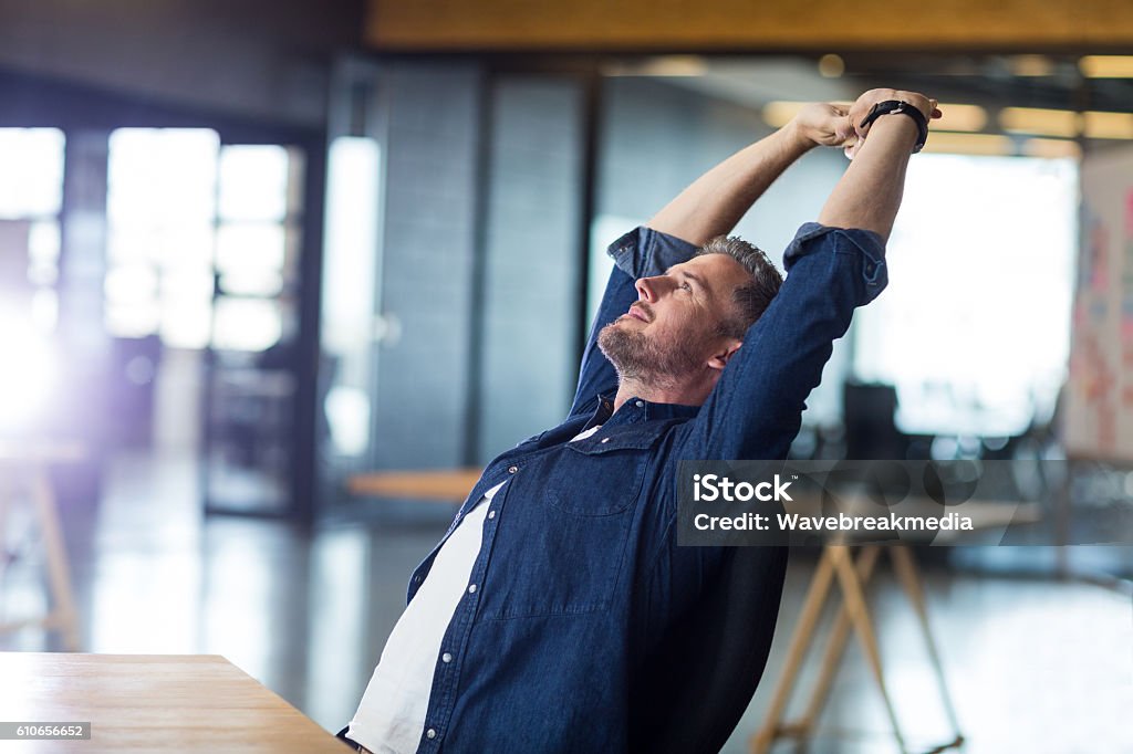 Relaxed man sitting in office Relaxed man sitting by table in office Adult Stock Photo