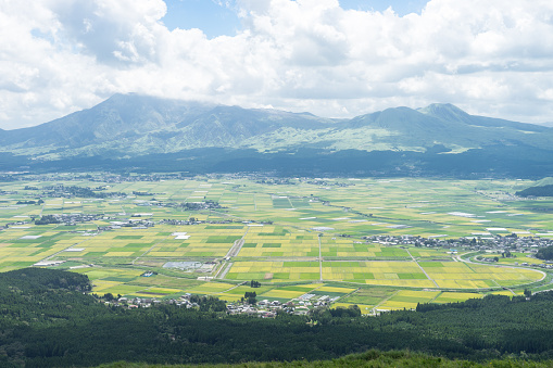 The view of Aso mountain. There is Aso mountain, rice field, town, forest and grasses in Japan.