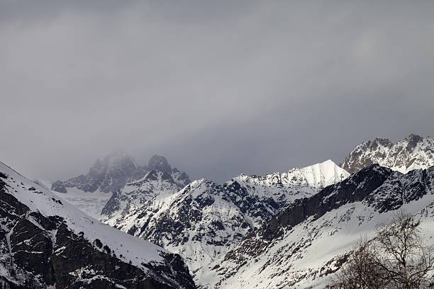 istock Snow sunlight mountain in fog at gray day before rain 610659040