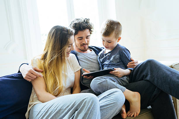 Cheerful Young Family Looking At Digital Tablet Together stock photo