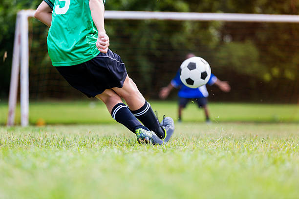 istock Soccer player kicks ball while goalie prepares to block 610662198