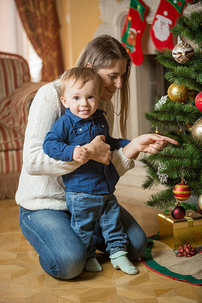 istock Mother and 10 months old baby boy decorating Christmas tree 610662340