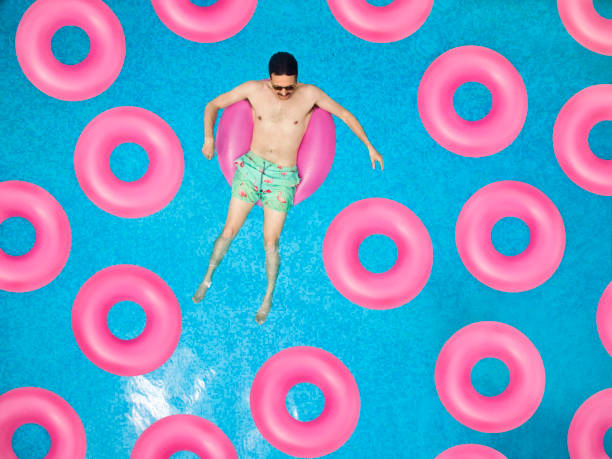 carefree man on ring in swimming pool - swimming pool water people sitting imagens e fotografias de stock