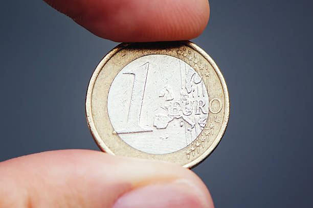 istock Businessman holding one euro coin between fingers 610668414