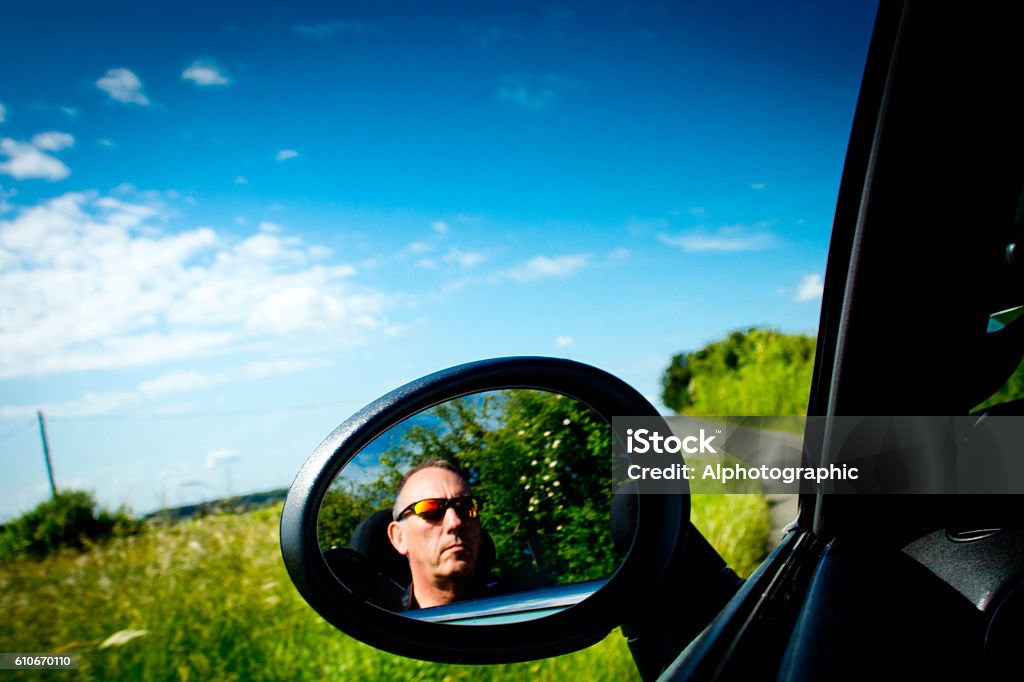 Mini Cooper interior A BMW Mini Cooper S convertible door mirror and background of the beautiful Cambridgeshire countryside. Mature male in sunglasses is visible in the door mirror. Black Color Stock Photo