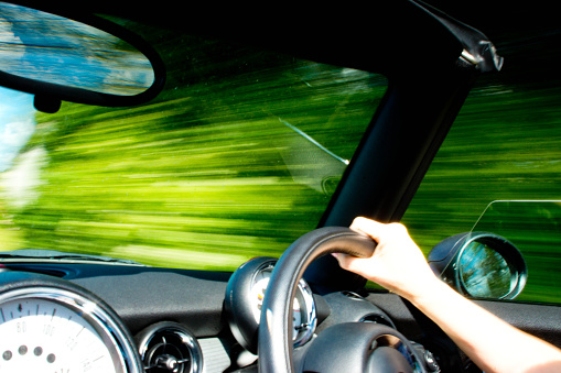 Cambridge, UK - June 27, 2015: A BMW Mini Cooper S convertible interior with the speedometer prominent in the image. The image was taken whilst the car was moving with a slow shutter speed therefore there is motion blur.