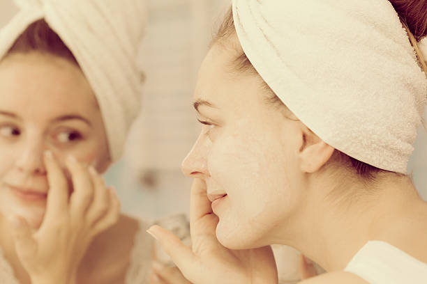 istock Woman applying mask cream on face in bathroom 610672618