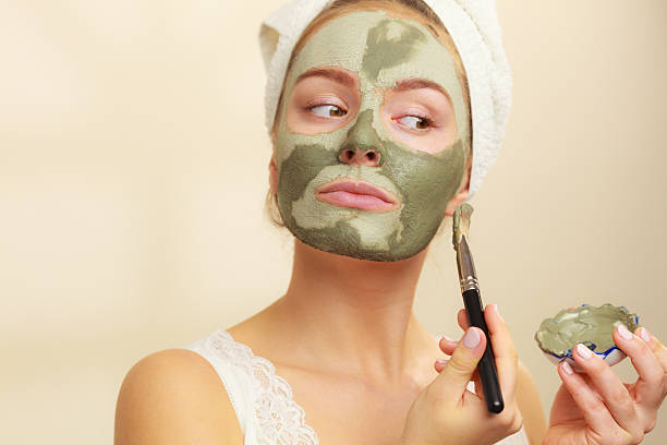 femme appliquant un masque de boue argile avec brosse pour le visage - bain de boue thérapie du bien être photos et images de collection
