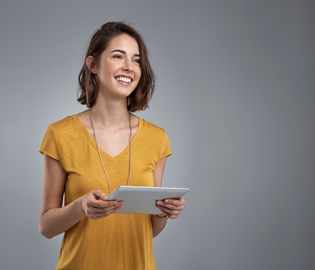Studio shot of an attractive young woman using a digital tablet against a gray background