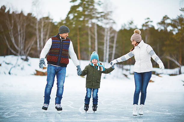 Family on ice-rink Modern family of father, mother and son skating in natural environment ice skating photos stock pictures, royalty-free photos & images
