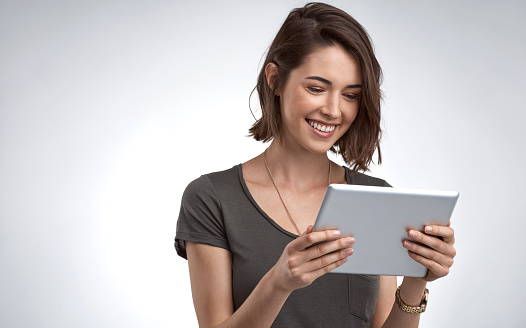 Studio shot of an attractive young woman using a digital tablet against a gray background