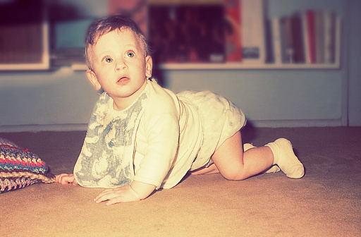 Vintage photo of a baby boy crawling at home.