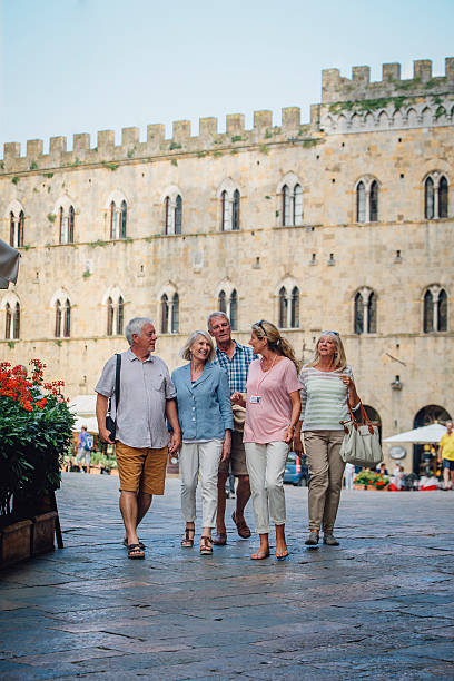 Two mature couples enjoying a tour of Italy. The tour guide is explaining local history.
