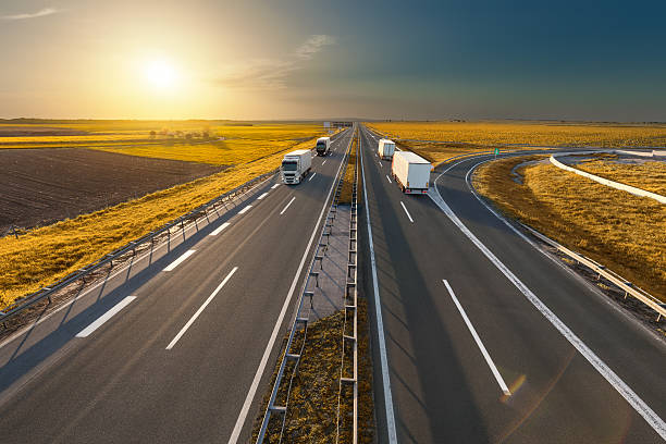 istock White trucks on the freeway at idyllic sunset 610682356