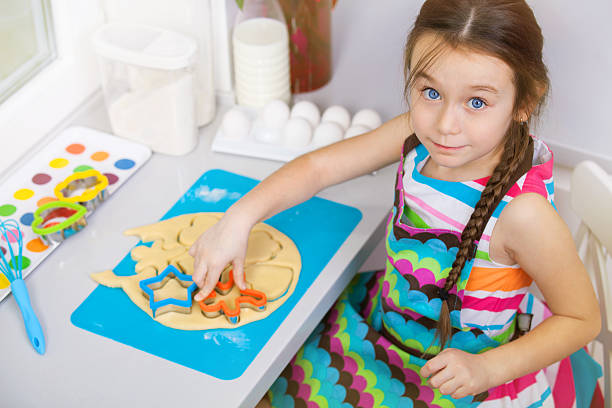 istock Little girl preparing a cookie on kitchen. 610683478