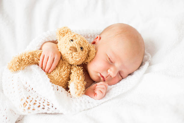 istock Newborn baby girl sleeping with teddy bear 610684750