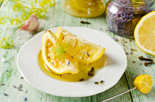 Preserved lemons with salt, lavender, garlic and cloves on a wooden table and spices on background
