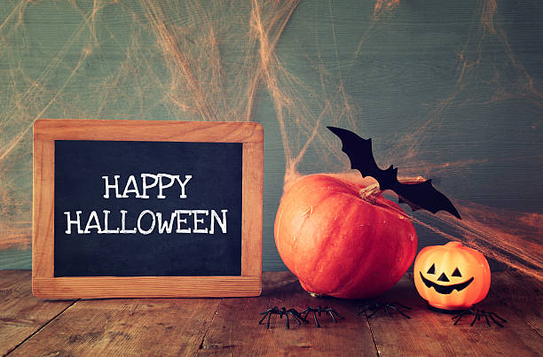 istock Cute pumpkins next to blackboard on wooden table 610692920