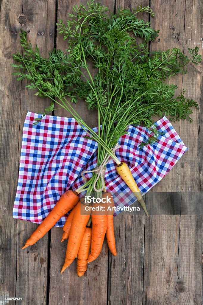 Bunch of fresh garden carrots with green leaves Bunch of fresh garden carrots with green leaves on dark wooden backdrop Agriculture Stock Photo