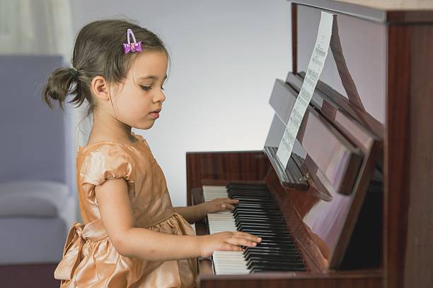 Little Girl Playing Piano Little girl is reading notes and practicing piano girl playing piano stock pictures, royalty-free photos & images