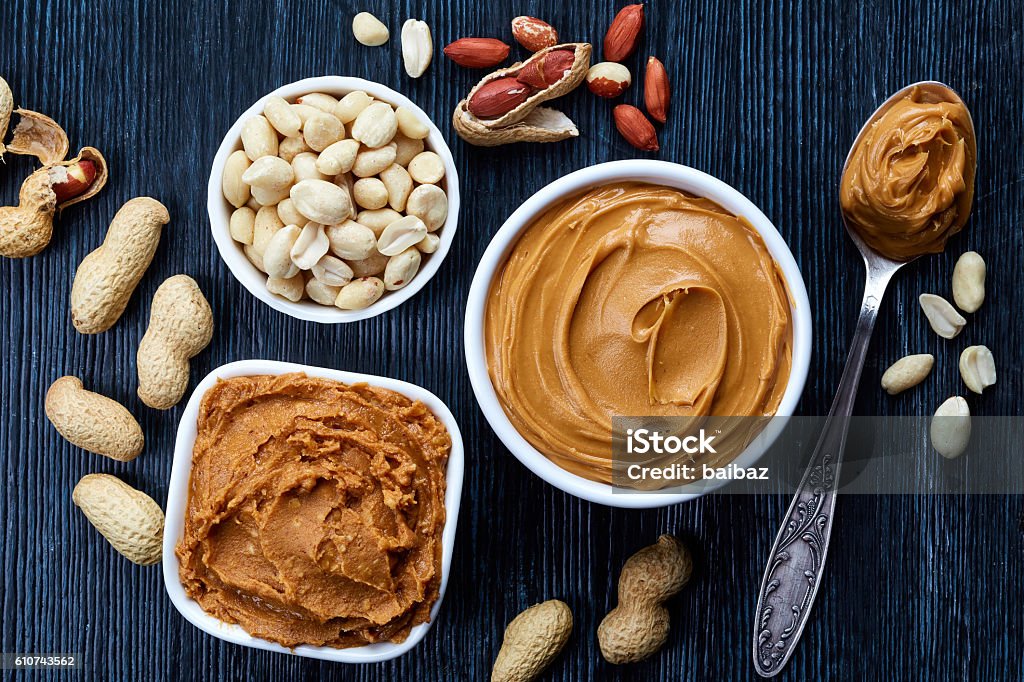 Peanut butter Two bowls of peanut butter and peanuts on dark wooden background from top view Butter Stock Photo