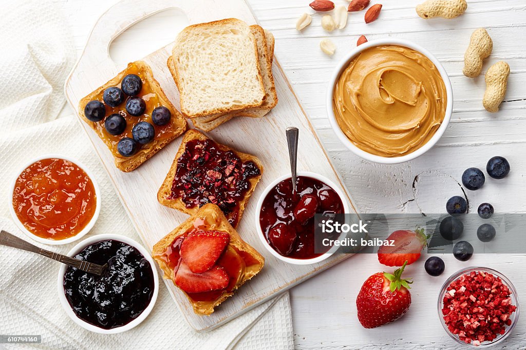 Peanut butter sandwiches Sandwiches with peanut butter, jam and fresh fruits on white wooden background from top view Preserves Stock Photo