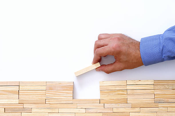 istock man hand putting brick over the gap 610744338