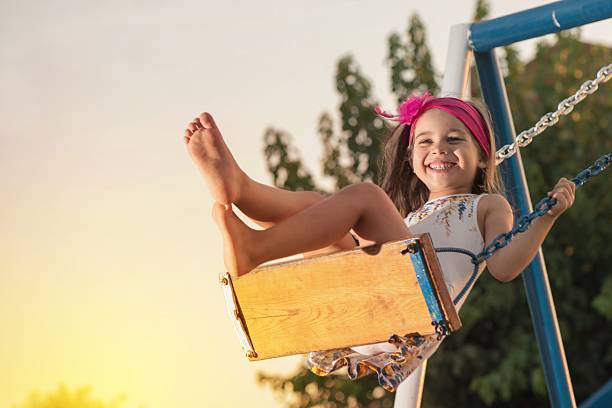 niña columpiándose en la puesta de sol - hamaca fotografías e imágenes de stock